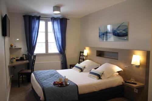 a bedroom with a bed with a tray of food on it at Logis Hotel Restaurant La Croisée des Chemins in Cayres