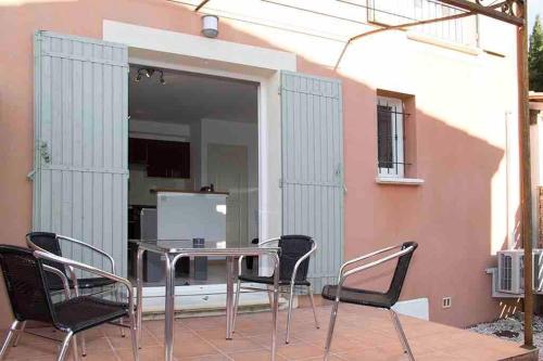 Un patio con una mesa y sillas en un balcón. en Gîte les coquelicots 2 Quartier résidentiel ( 2 * ), en LʼIsle-sur-la-Sorgue
