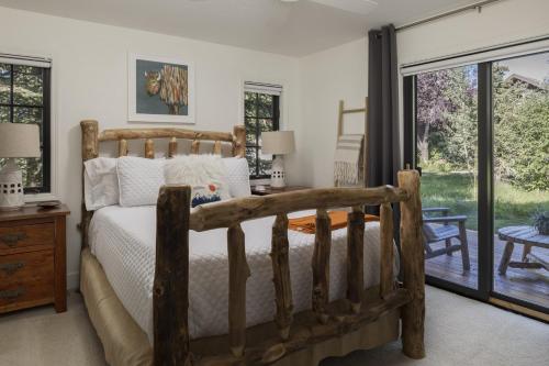 1 dormitorio con cama de madera y puertas correderas de cristal en Tailwind Cabin Creek Front - Close to Targhee, en Driggs