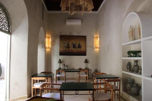 uma sala com mesas e cadeiras e um quadro na parede em Riad Emberiza Sahari em Marrakech