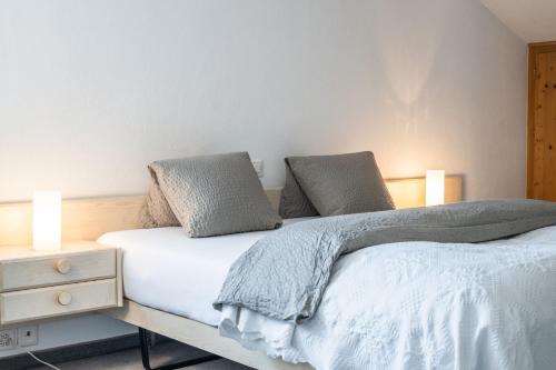 - une chambre avec un lit avec deux oreillers et une table de nuit dans l'établissement Hotel Alpina, à Schiers