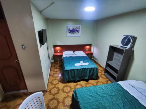 una camera d'albergo con due letti e una televisione di Hostal Continental a Nazca
