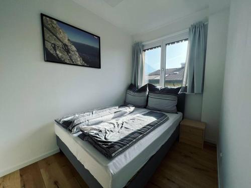 Bett in einem Zimmer mit einem großen Fenster in der Unterkunft Bergpanorama Lodge — Alpenidylle in Thaur