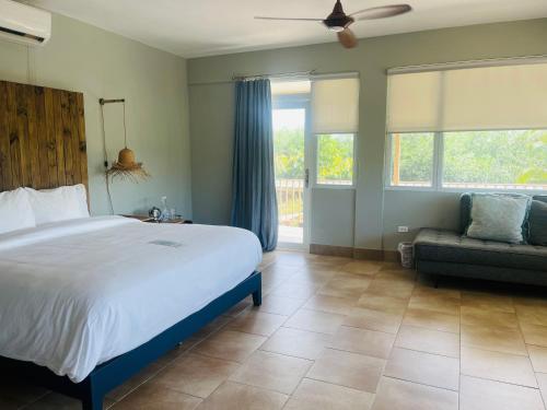 a bedroom with a bed and a couch and windows at Numero Uno Piñones in Loiza