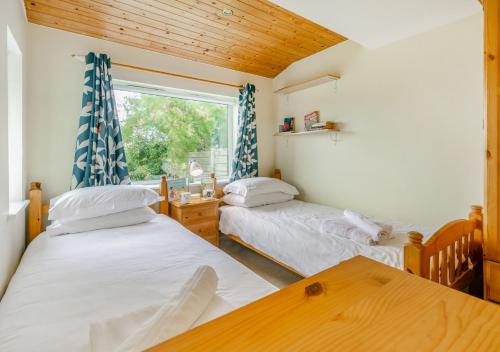 two twin beds in a room with a window at Curlews Trevone in Padstow