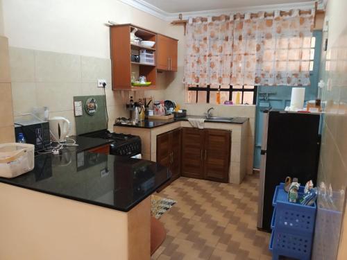 CeeJ'S Airbnb في Meru: مطبخ مع كونتر اسود توب وثلاجة