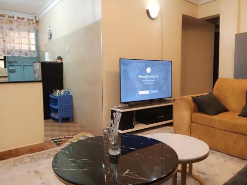 CeeJ'S Airbnb في Meru: غرفة معيشة مع تلفزيون وطاولة