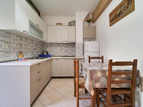 een keuken met een tafel en stoelen en een koelkast bij Sea Breeze Rooms in Himare