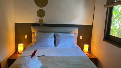 1 dormitorio con 1 cama con 2 velas y 2 lámparas en Pousada Bambu Dourado en Marau