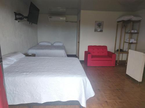 a bedroom with a bed and a red chair at Villas El Alto 1 in Tambor