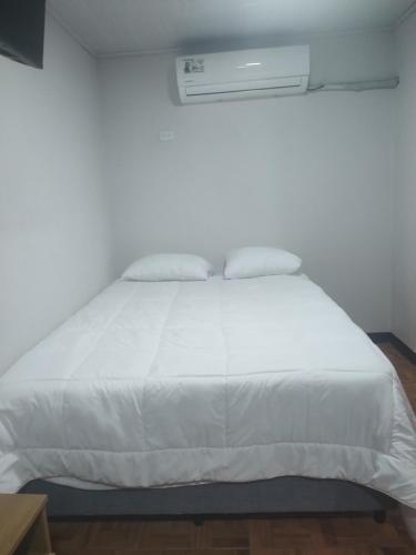 a white bed with white sheets and pillows on it at Villas El Alto 1 in Tambor