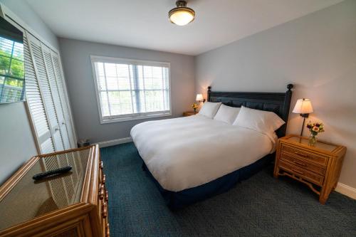 a bedroom with a large white bed and two windows at Sandpiper Beach Club in Cape May