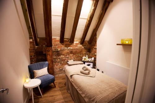 1 Schlafzimmer mit 2 Betten und einem blauen Stuhl in der Unterkunft Seckford Hall Hotel & Spa in Woodbridge