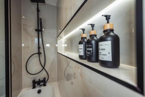 three black bottles sitting on a shelf in a bathroom at Exquisite 6 Bedroom Luxury Home Manchester in Manchester