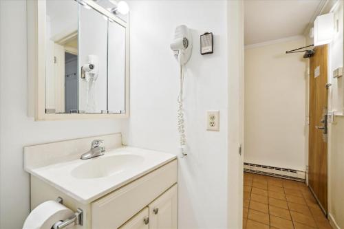 a white bathroom with a sink and a mirror at Ski home to this cozy one bedroom condo Whiffletree F5 in Killington