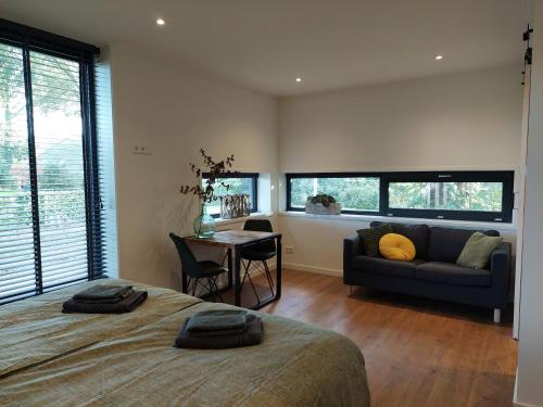ein Schlafzimmer mit einem Bett, einem Sofa und einem Tisch in der Unterkunft Smaakvol Slochteren in Slochteren