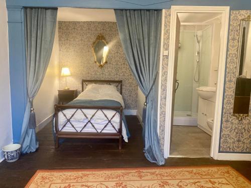 1 dormitorio con 1 cama con cortinas azules y baño en Moon River Bellac Chambre d'hotes, en Bellac