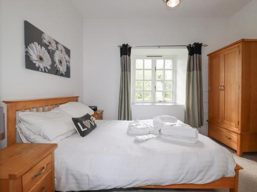 a bedroom with a large white bed and a window at Nest Cottage in Bodmin