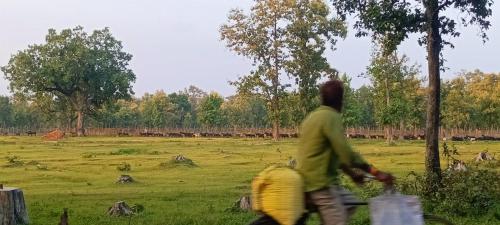 a man is riding a bike in a field at Namaste Homestay in Khajurāho