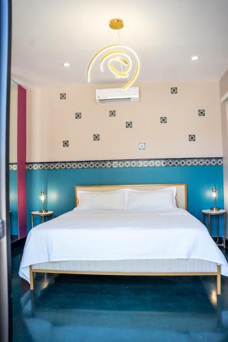 a bedroom with a white bed with a chandelier at Catrina Valle - Ubicación 10 in Valle de Guadalupe