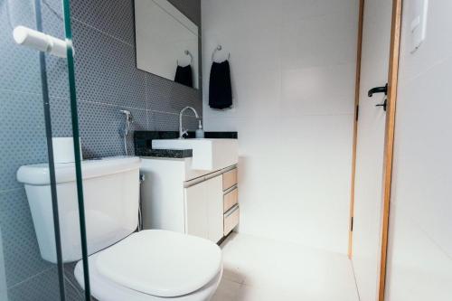 uma casa de banho com um WC branco e um lavatório. em Apartamentos modernos e aconchegantes no centro. em Poços de Caldas