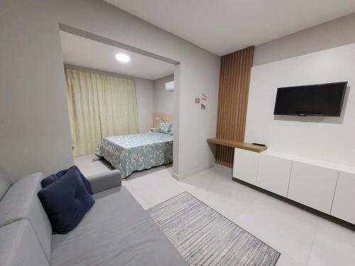 salon z kanapą i łóżkiem w obiekcie Apartamentos modernos e aconchegantes no centro. w mieście Poços de Caldas