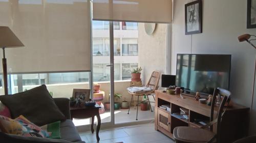 a living room with a tv and a large window at Habitación acogedora con baño privado cerca de la Playa in La Serena