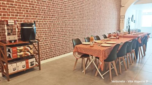 a dining room with tables and chairs and a brick wall at Séjour en famille ou entre amis: Sauna, Billard in Bains-les-Bains