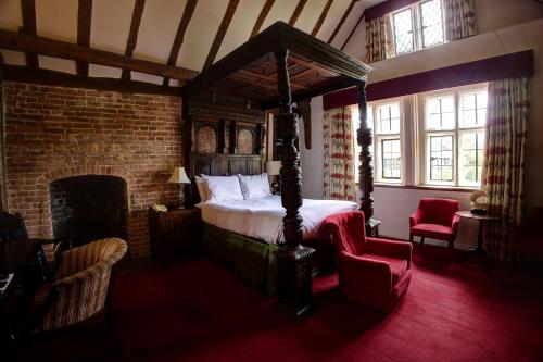 a bedroom with a canopy bed and a fireplace at Seckford Hall Hotel & Spa in Woodbridge