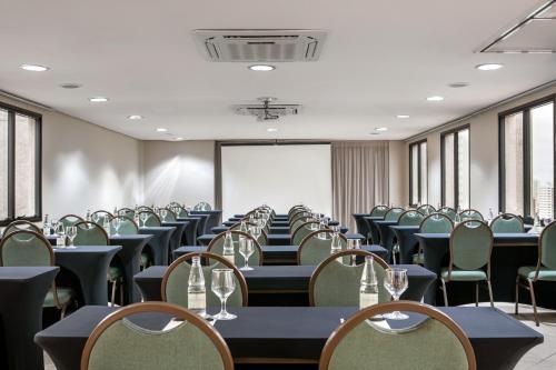 a conference room with tables and chairs and a screen at São Paulo Tatuape, Affiliated by Meliá in Sao Paulo