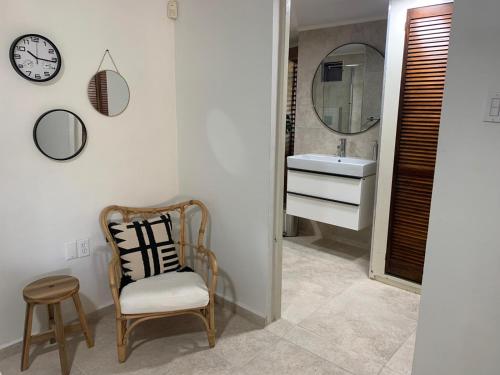 uma casa de banho com uma cadeira, um lavatório e um espelho. em Piscadera Bay Resort #16 em Dorp Sint Michiel