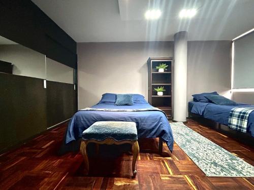 1 dormitorio con 2 camas con sábanas azules y taburete en Luxury Apartment Masaryk 4BR, en Ciudad de México