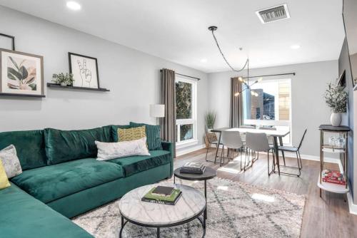 a living room with a green couch and a table at Walk to Downtown Broadway with Pool, Free Parking, and Gym in Nashville