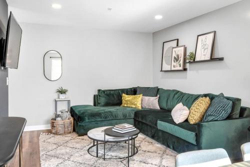 a living room with a green couch and a table at Walk to Downtown Broadway with Pool, Free Parking, and Gym in Nashville