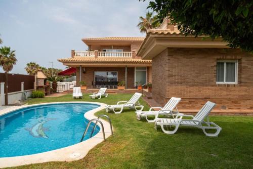 a house with a swimming pool with chairs and a house at Blended in Calafell