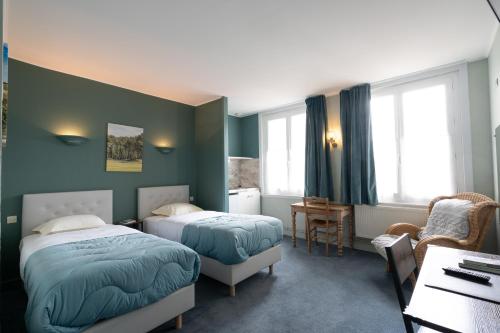 a hotel room with two beds and a desk at Logis - Hôtel Le Caddy in Le Touquet-Paris-Plage