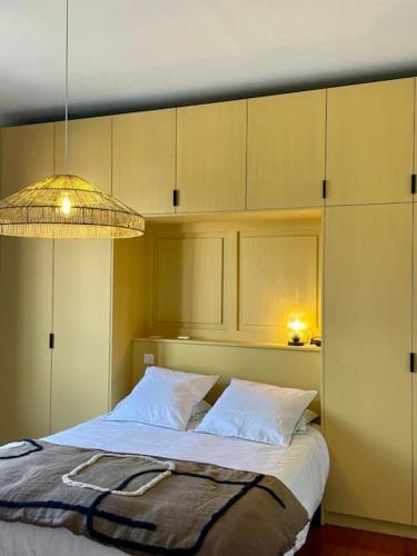 - une chambre avec un lit doté d'oreillers blancs et d'une lampe dans l'établissement Appartement neuf style Art Déco au Bouscat, à Le Bouscat