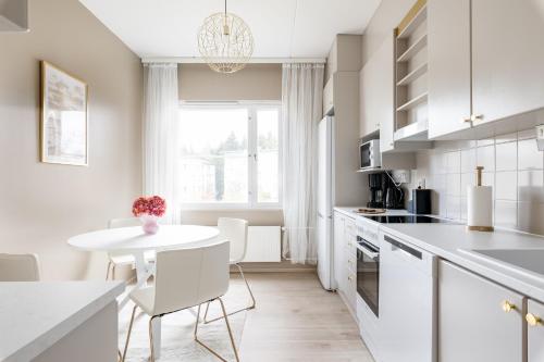 a white kitchen with a white table and chairs at Cozy Room x Aurora Lights in Tampere