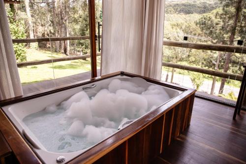 a bath tub filled with foam in front of a window at Refúgio do Caracol Pipas e Chalés in Canela