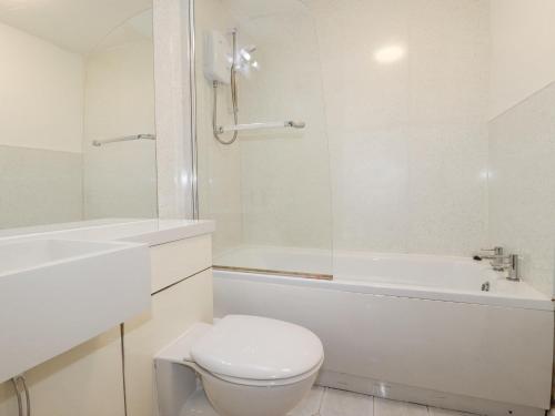 a white bathroom with a toilet and a bath tub at Minions Cottage in Bodmin