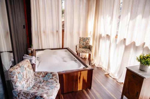 a bath tub in a living room with a chair and a couch at Refúgio do Caracol Pipas e Chalés in Canela