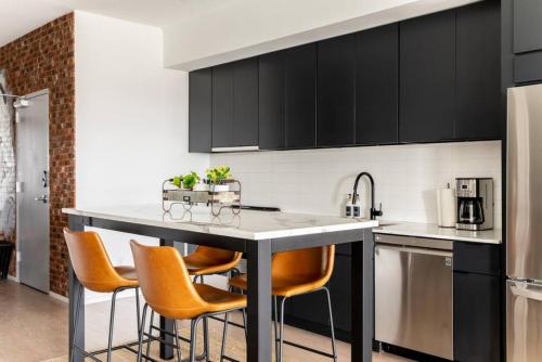 a kitchen with black cabinets and orange chairs at Stunning River View Condo Walk to Downtown Rooftop Patio in Nashville