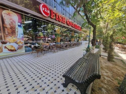 a bench on a sidewalk in front of a restaurant at City Center Apartment 1 in Tashkent