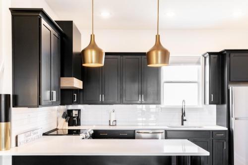 a kitchen with black cabinets and gold pendant lights at Diamond Retreat Townhome 7 Beds 3 mi to Downtown in Nashville