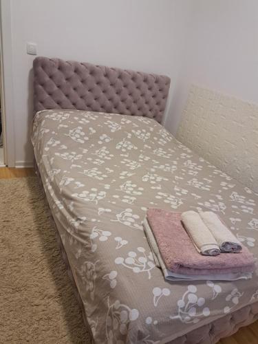 a bed with a blanket and two towels on it at Sara apartman in Novi Grad