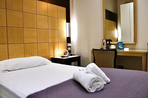 una camera d'albergo con un letto e asciugamani di Hotel Fiorella Milano a Milano
