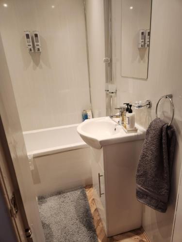 a white bathroom with a sink and a bath tub at Largs holiday flat in Largs