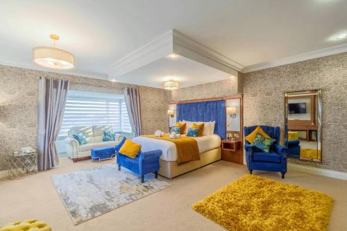 a bedroom with a bed and two blue chairs at Kilmorey Arms Hotel in Kilkeel