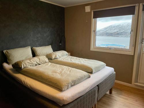 two beds sitting in a room with a window at Penthouse with panorama view and great location! in Tromsø