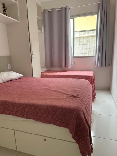 1 dormitorio con 2 camas y ventana en Apto 2 Quartos Perfeito en Guarapari